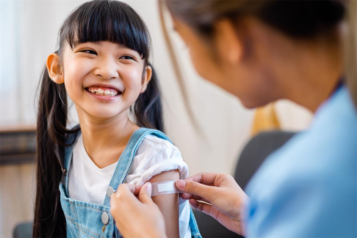 Childhood vaccination. Asian young woman doctor vaccinating little girl.
